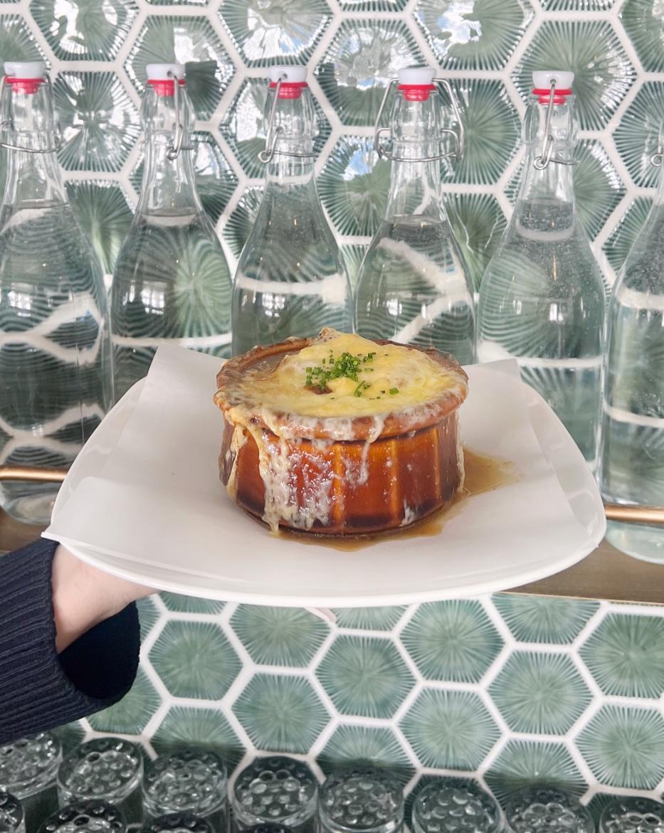 french onion soup on a plate in front of tiled wall